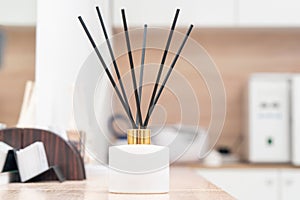 Aroma diffuser for perfumed liquid and reed sticks in the room on a wooden table