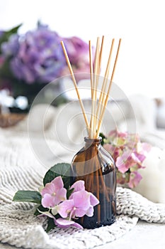 The aroma diffuser with the stick perfume and flowers on a blurred background.