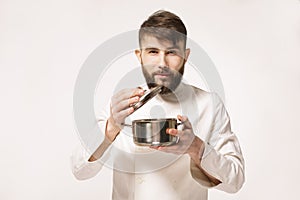 Aroma of a dish. Head chef smelling the food standing against white background. Chef smelling the aroma of a dish.