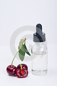 Aroma and flavor enhancer next to a ripe cherry, on a white background photo