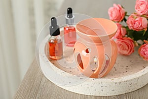 Aroma lamp, roses and essential oils on wooden table