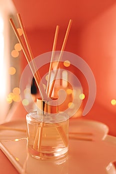 Aroma liquid fragrance with wooden sticks with glowing lights and skin care products close up in room. Wellness