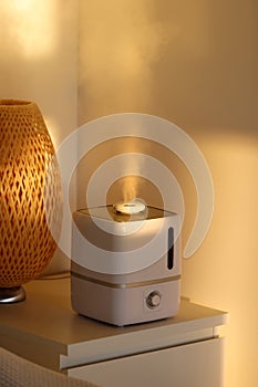 Aroma oil diffuser on the table at home, steam from the air humidifier