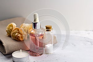 Aroma oil sea salt bottles fresh flowers on towel marble table