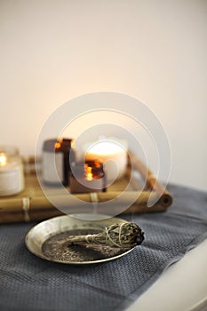 Aroma smudge stick burning on metal plate in front of candles