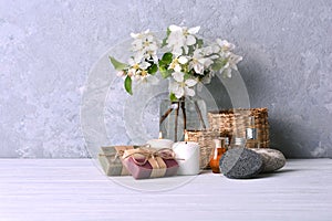 Aroma spa treatment background with handmade soap, aroma candles, flowers, aromatic oils and stones on the shelf