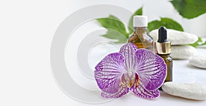 Aromatherapy concept with essential oil bottle, dropper, pebbles and orchid flowers