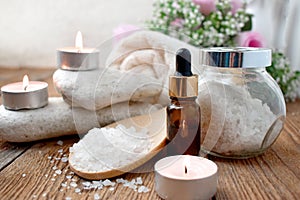 Aromatherapy concept with essential oil bottle, sea salt, burning candles and pebbles.