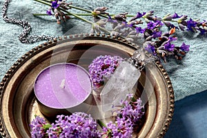 Aromatherapy and flowers close-up. Scented candle and perfume vial with verbena and lavender flowers