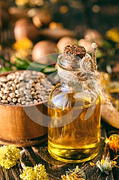 Aromatherapy massage oil with herbs, nuts and seeds on a wooden background.