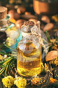 Aromatherapy massage oil with herbs, nuts and seeds on a wooden background.