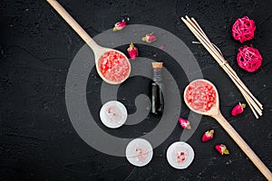 Aromatherapy for relax concept. Rose buds, spa salt, candles and oil on black background top view copyspace