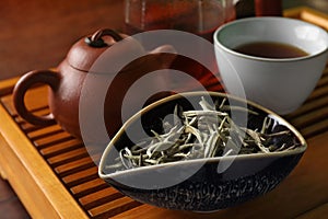 Aromatic Baihao Yinzhen tea and teapot on wooden tray, closeup. Traditional ceremony