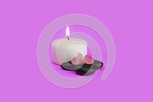 Aromatic candle and stones with a flower on pink background photo