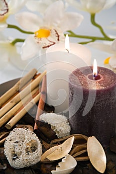 Aromatic candles burn on a dish with an orchid