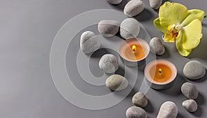 Aromatic  candles, orchid flower and stones on a gray background.  Spa composition. Relaxation and zen like concept