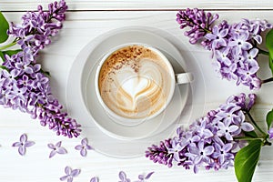 aromatic cappuccino with heart latte art surrounded by lilac flowers on a white background