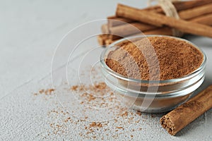 Aromatic cinnamon powder and sticks on grey table, closeup. Space for text