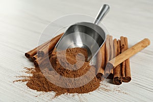 Aromatic cinnamon powder and sticks on white table, closeup