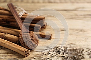 Aromatic cinnamon powder and sticks on wooden table, closeup. Space for text