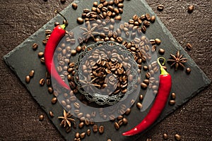 Aromatic coffee beans in a metal Turkish bowl, anise with bitter hot chili pepper on a black background