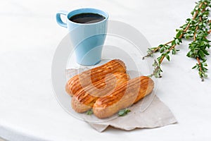 Aromatic coffee in a blue cup with eclairs in a summer cafe