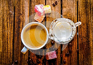 Aromatic coffee in a white cup with a glass milk jug next to it,