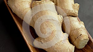 Aromatic fresh ginger root in a kitchen wooden bowl. Whole medicinal rhizome.