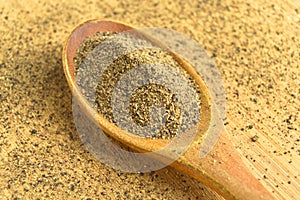 Aromatic fresh powdered black pepper ground, in spoon on wooden bamboo cutting board
