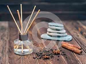 Aromatic freshener with reed sticks is on the brown wooden table. Close up