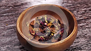 Aromatic herbal tea with dried flower petals and fruit pieces close up.