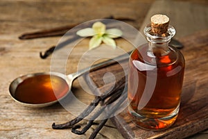 Aromatic homemade vanilla extract on wooden table. Space for text photo