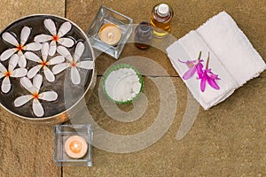 Aromatic oil, burned candle, pink flowers, white towel on vintage grunge stone background