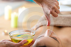Aromatic oil dripping from finger at Ayurvedic massage.
