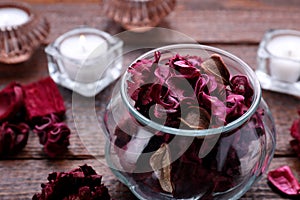 Aromatic potpourri of dried flowers in glass jar on wooden table, closeup