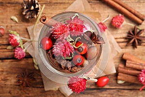 Aromatic potpourri in glass jar on wooden background, flat lay