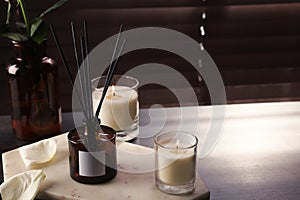 Aromatic reed air freshener and burning candles on white windowsill, space for text