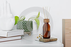 Aromatic reed air freshener, chamomiles and houseplant on white table