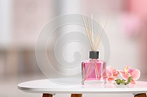 Aromatic reed air freshener and flowers on table