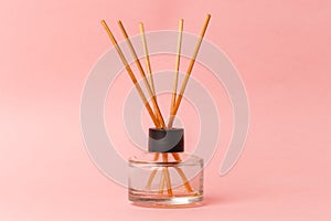 Aromatic reed air freshener on pastel pink background. Air freshener. Perfume composition in a glass diffuser with reed sticks