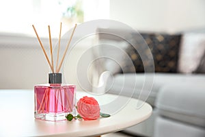 Aromatic reed air freshener and rose on table