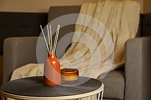 Aromatic reed air freshener and scented candle on table indoors