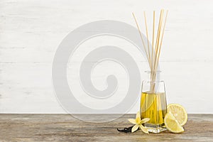 Aromatic reed freshener, lemon and vanilla on wooden table against light background.