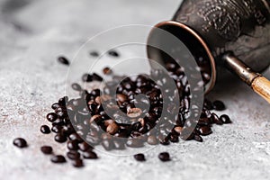 Aromatic roasted coffee beans spill out of vintage metal turk. Concept of coffeemania, morning ritual, delicious and stroung drink