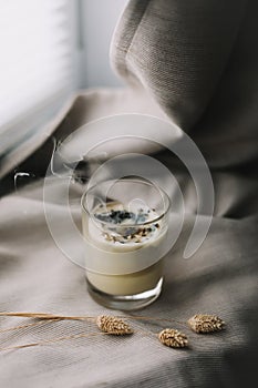 aromatic scented candle with smoke on beige textile background.