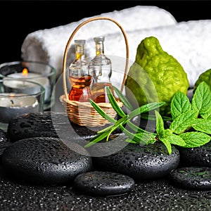 Aromatic spa still life of bottles essential oil, fresh mint, rosemary, bergamot fruits, towels and candles on zen stones
