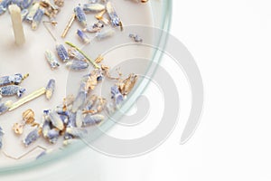 Aromatized gray light candle with small lavender dry flowers on glass