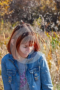 Around the girl with red hair, fluff from the cattail flies.