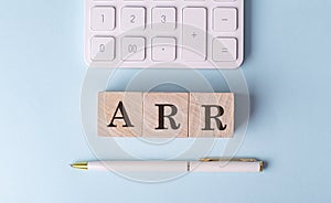 ARR on wooden cubes with pen and calculator, financial concept