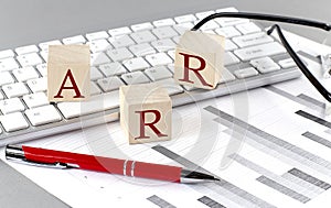 ARR written on a wooden cube on the keyboard with chart on grey background